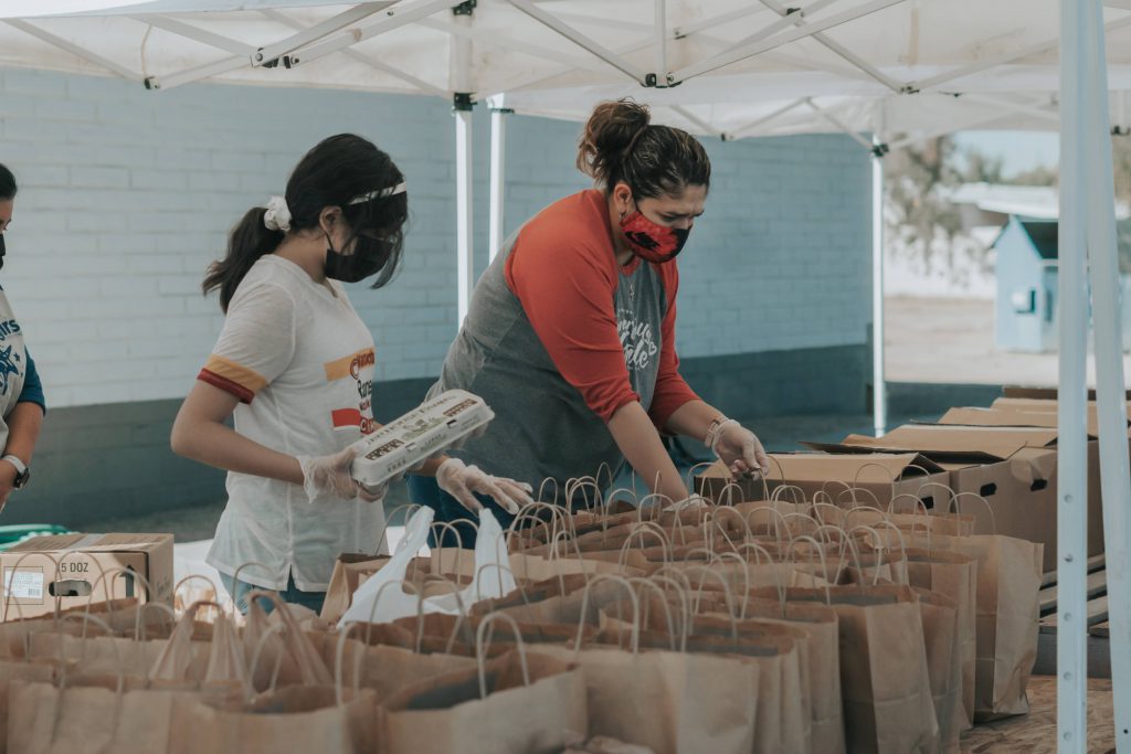 Two volunteers help load grocery bags. 