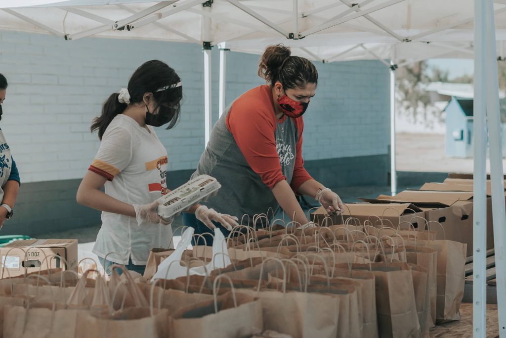 Two volunteers help load grocery bags.