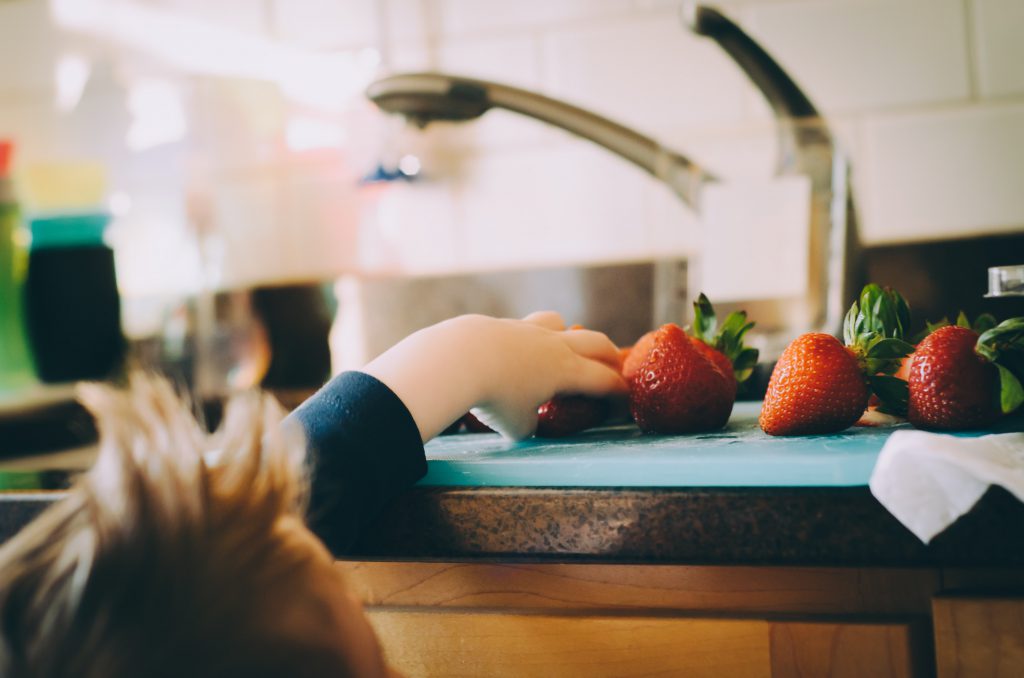 Child reaches for a strawberry.