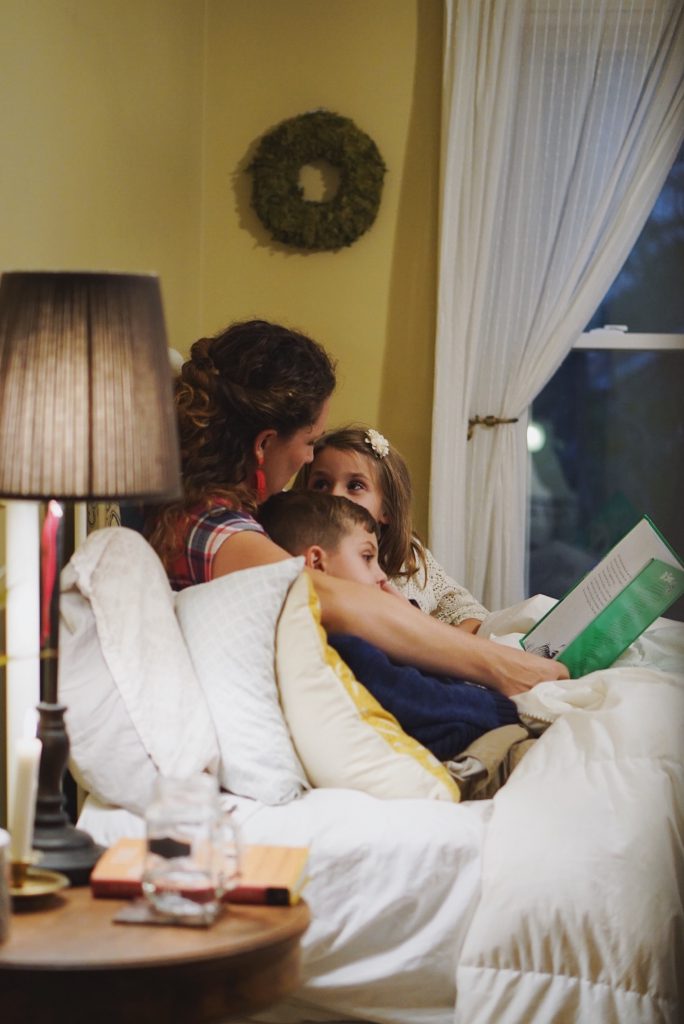A mother reads to her children in bed.